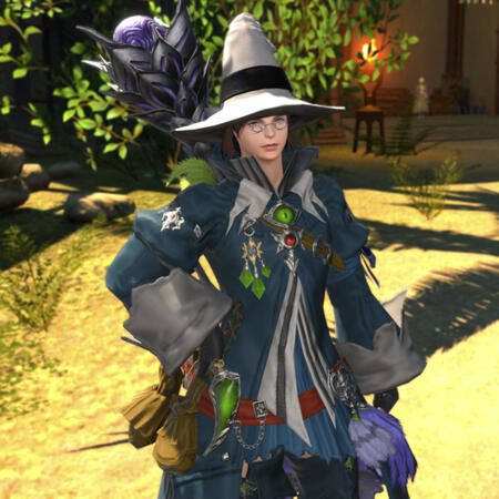 Kheda in mage robes with various adornments. He stands with his hand on his hip, wearing a big mage's hat and spectacles.